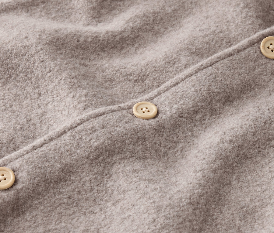 Detail šedé vlněné látky se třemi béžovými knoflíky.