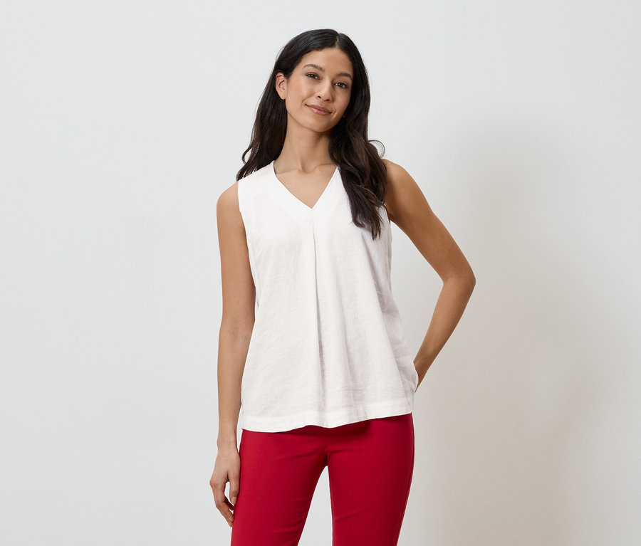 Žena má na sobě bílý top bez rukávů a červené kalhoty.