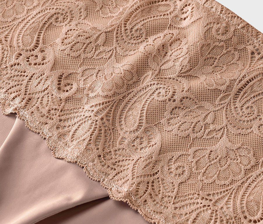 Detail béžové krajky na béžové látce.