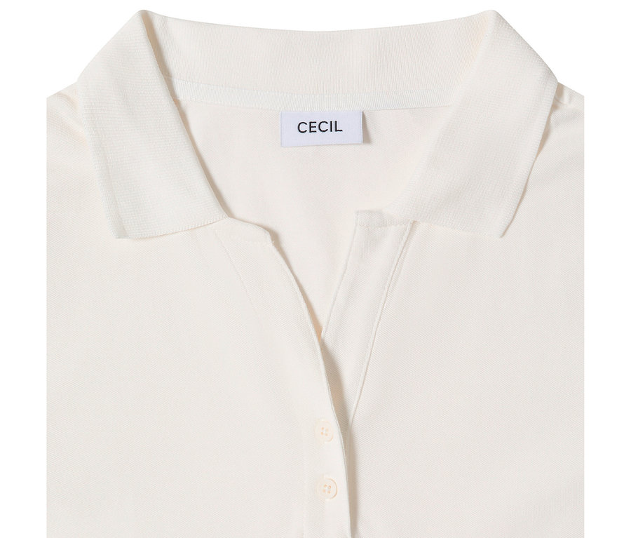 Detail bílé 3/4 polokošile CECIL, zobrazující límeček, výstřih do V s knoflíkovou légou se dvěma světlými knoflíky a značkový štítek 'CECIL'.