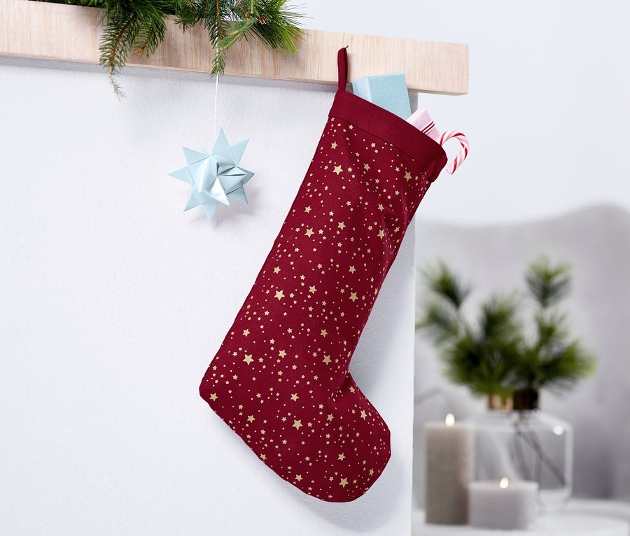 Vínová Mikulášská punčocha se zlatými hvězdami visí na zdi.