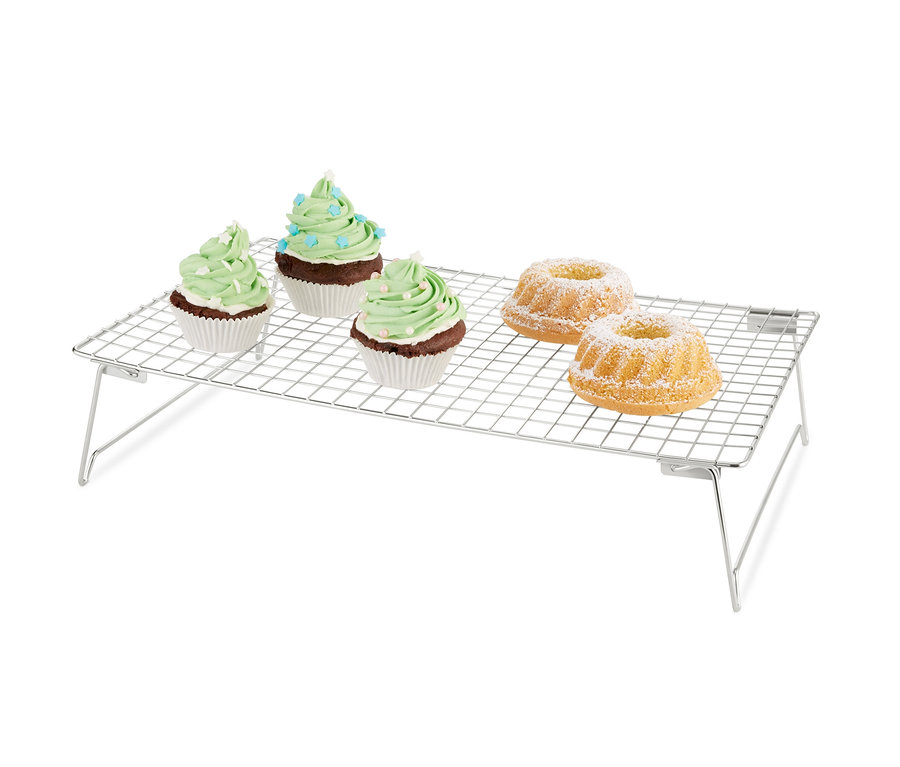 Tři muffiny se zeleným zdobením a dvě bábovky s moučkovým cukrem na třípatrové odkládací mřížce.