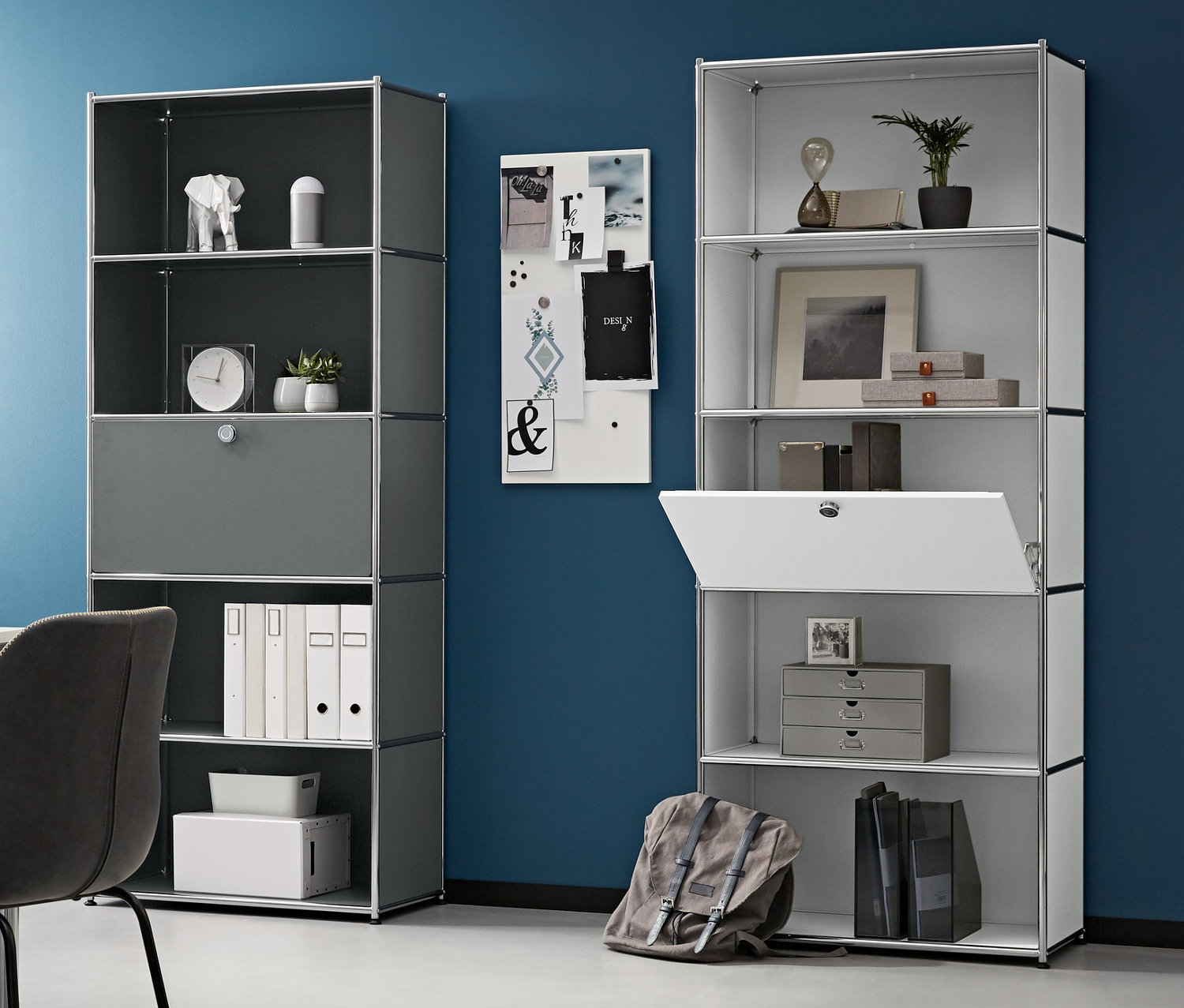 Pokoj s pracovním stolem, židlí a dvěma vysokými kovovými regály s přemístitelnými výklopnými dvířky. Vlevo je kovová skříňka na kolečkách a na stole je notebook.