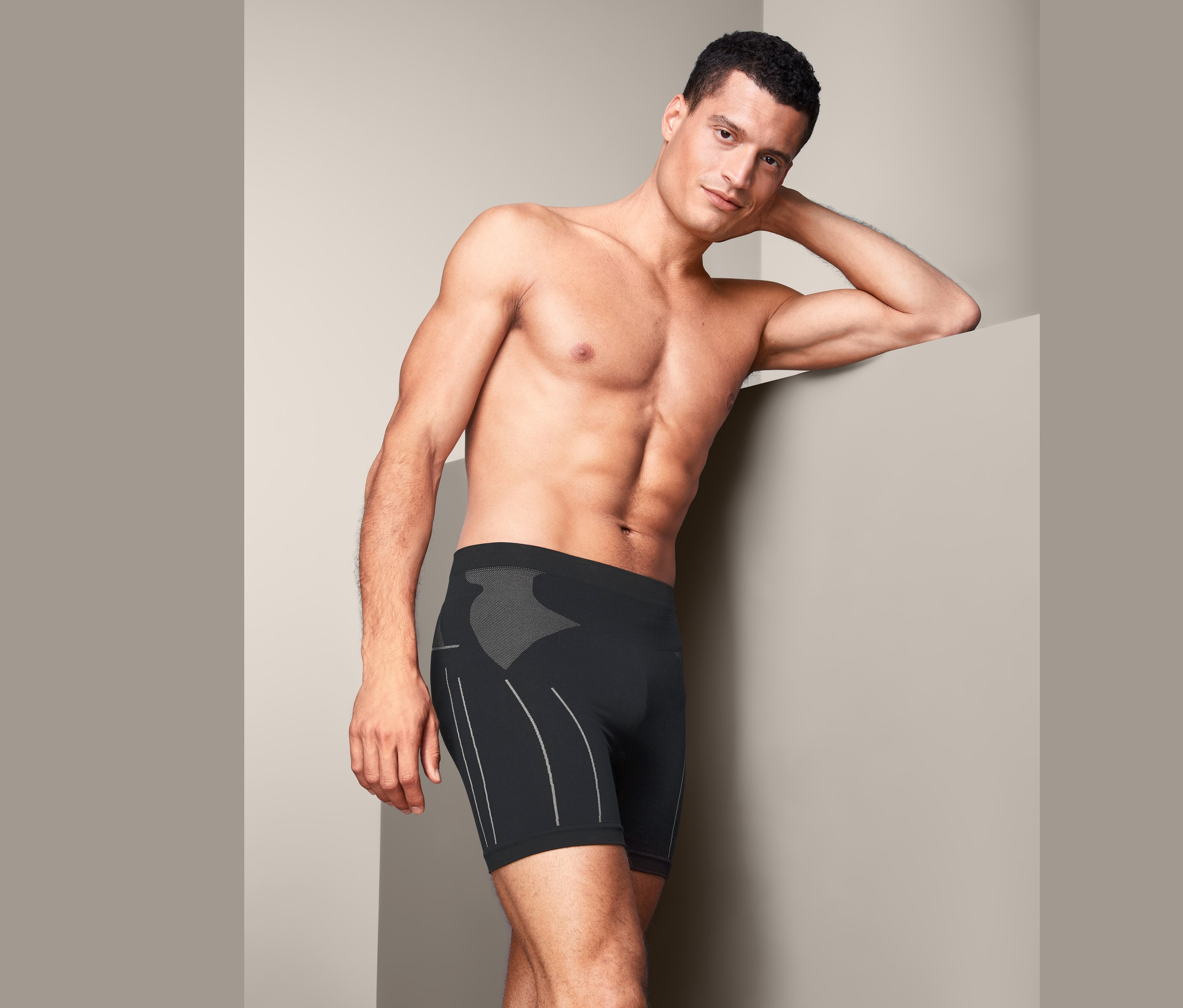 Muž opírající se o zeď v černých cyklistických spodkách.