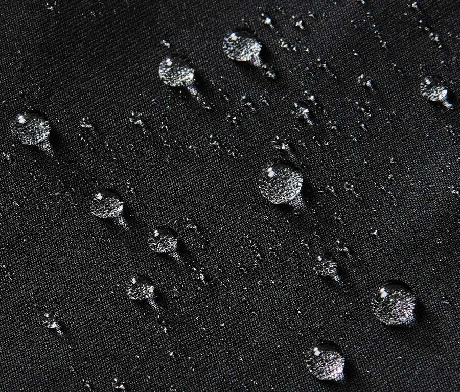 Detailní záběr na černé vodoodpudivé sportovní legíny s kapkami vody na povrchu.