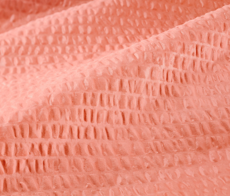 Detailní záběr na krepové povlečení standardní velikosti v lososové barvě.