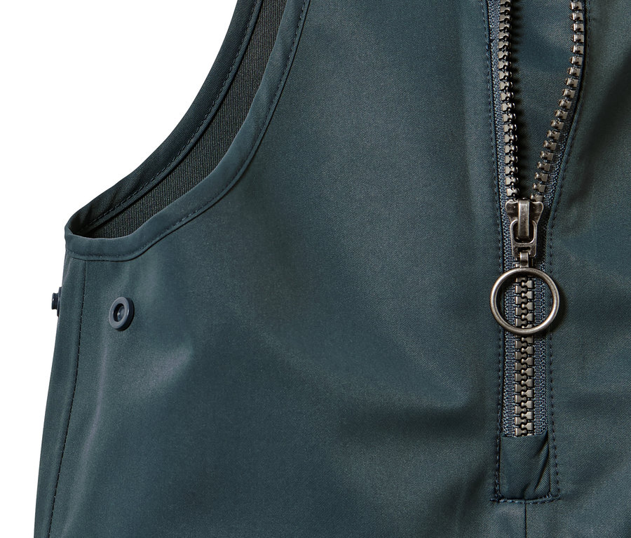 Detail dětských kalhot do deště se zipem a knoflíkem.