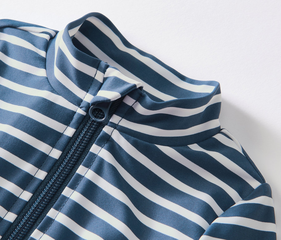 Detail dětského overalu s UV ochranou 80 s modrými a bílými proužky a zipem.