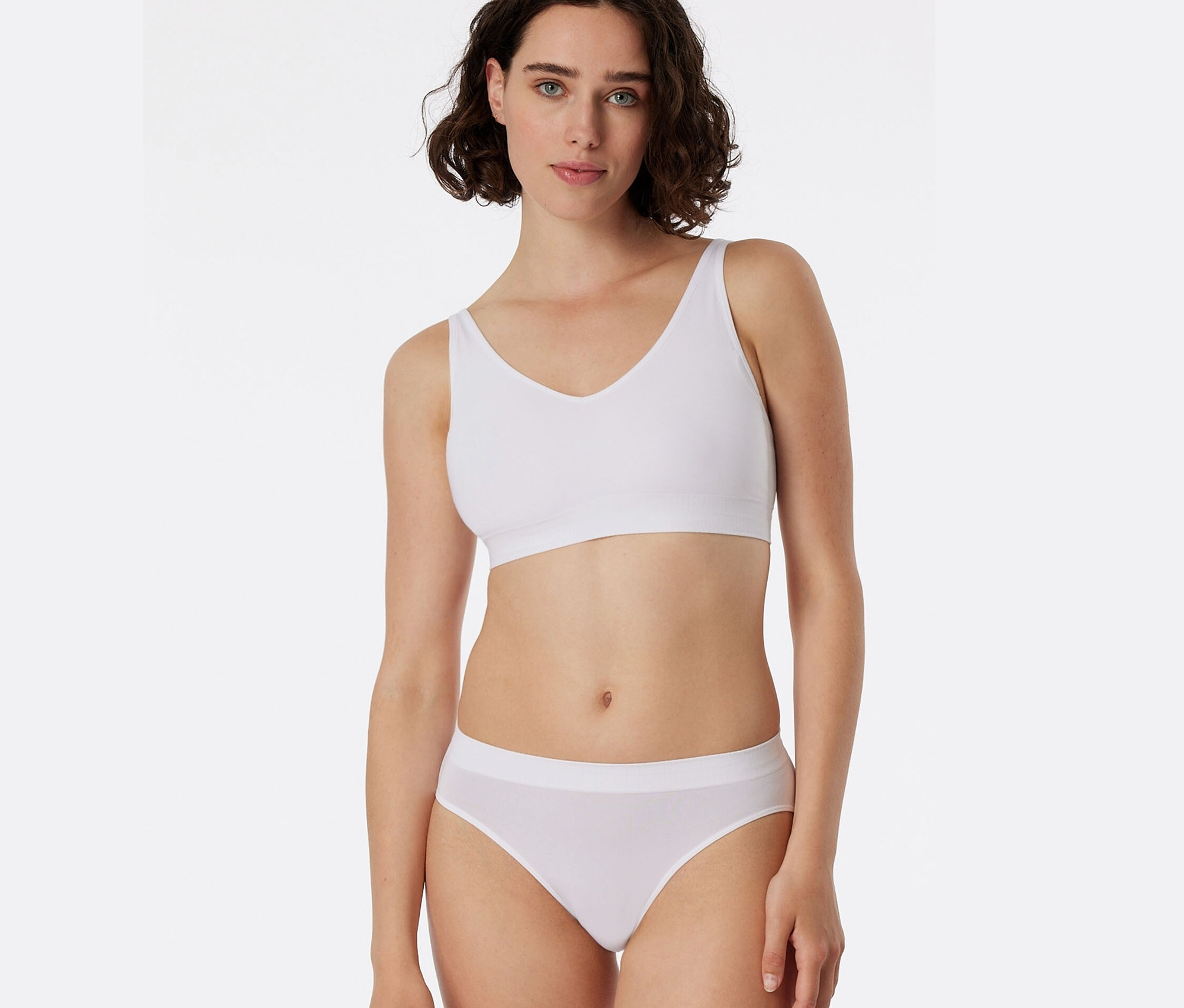 Žena má na sobě bílou sportovní podprsenku a bílé kalhotky Rio SCHIESSER.