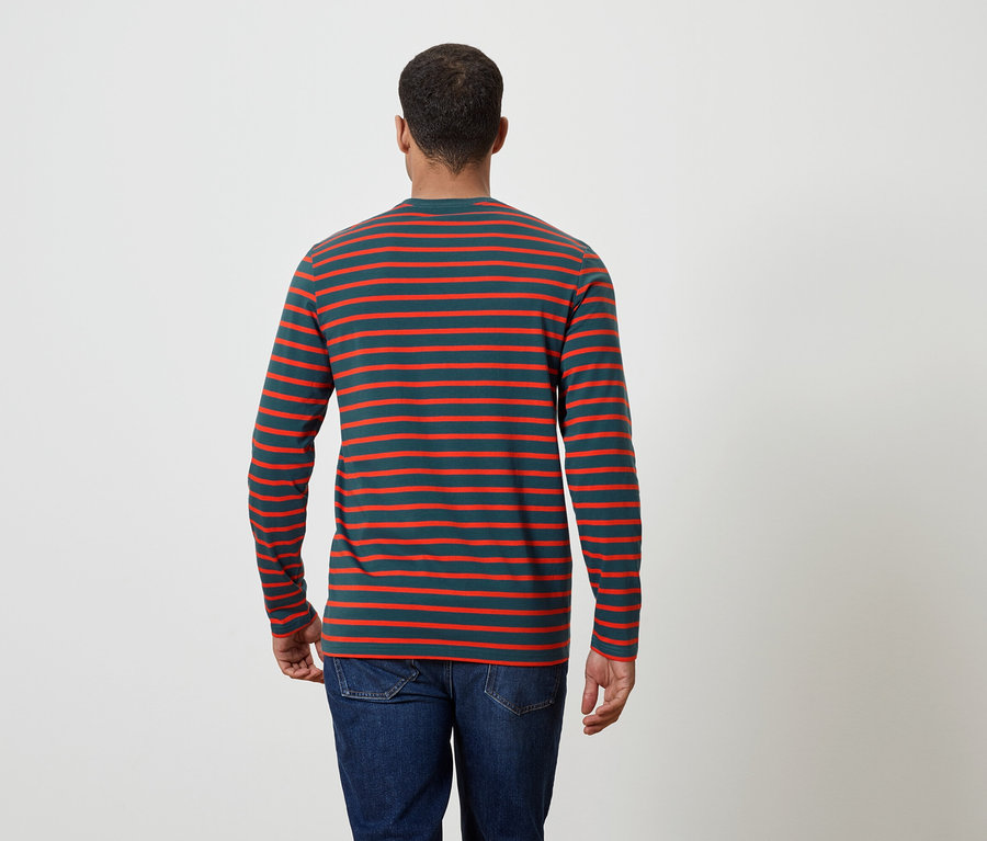 Muž zády ke kameře má na sobě pruhované tričko s dlouhým rukávem a džíny.