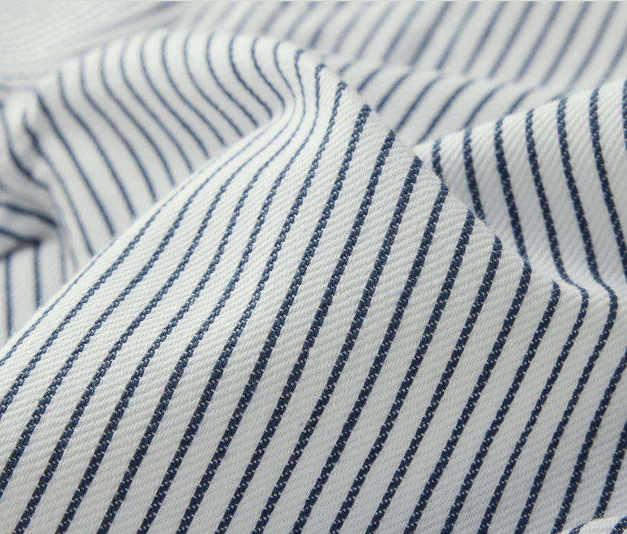 Detailní záběr na dětské tkané kalhoty s modrými proužky na bílém pozadí.