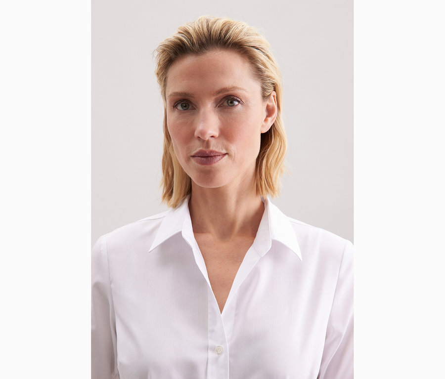Žena má na sobě bílou halenku Seidensticker Slim Fit non iron.