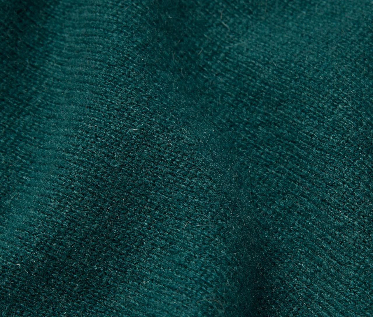 Detailní záběr na smaragdově zelenou látku s texturou.