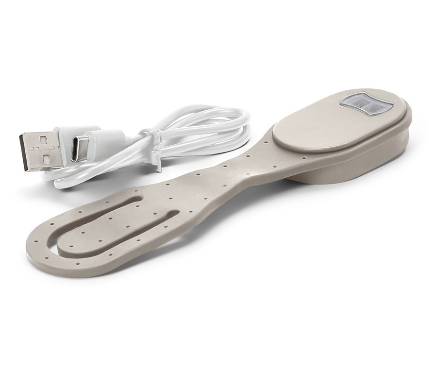 Béžový klip na knihy se světlem a přiloženým nabíjecím USB kabelem leží na bílém pozadí.