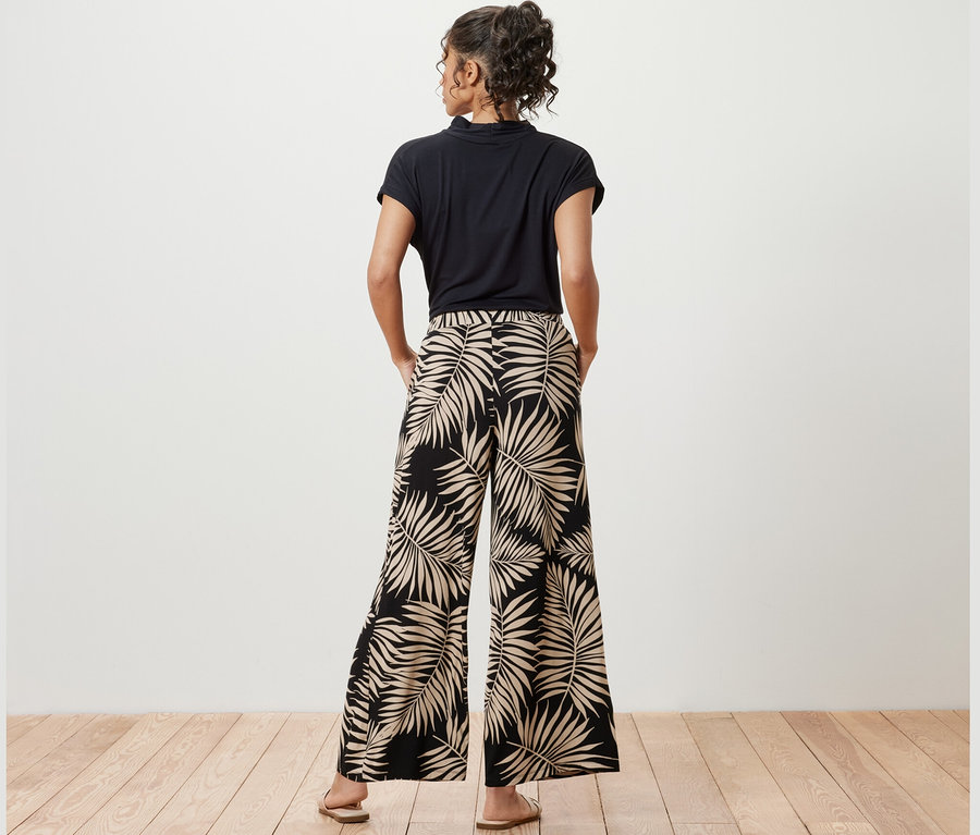 Žena pózuje v širokých kalhotách s potiskem.