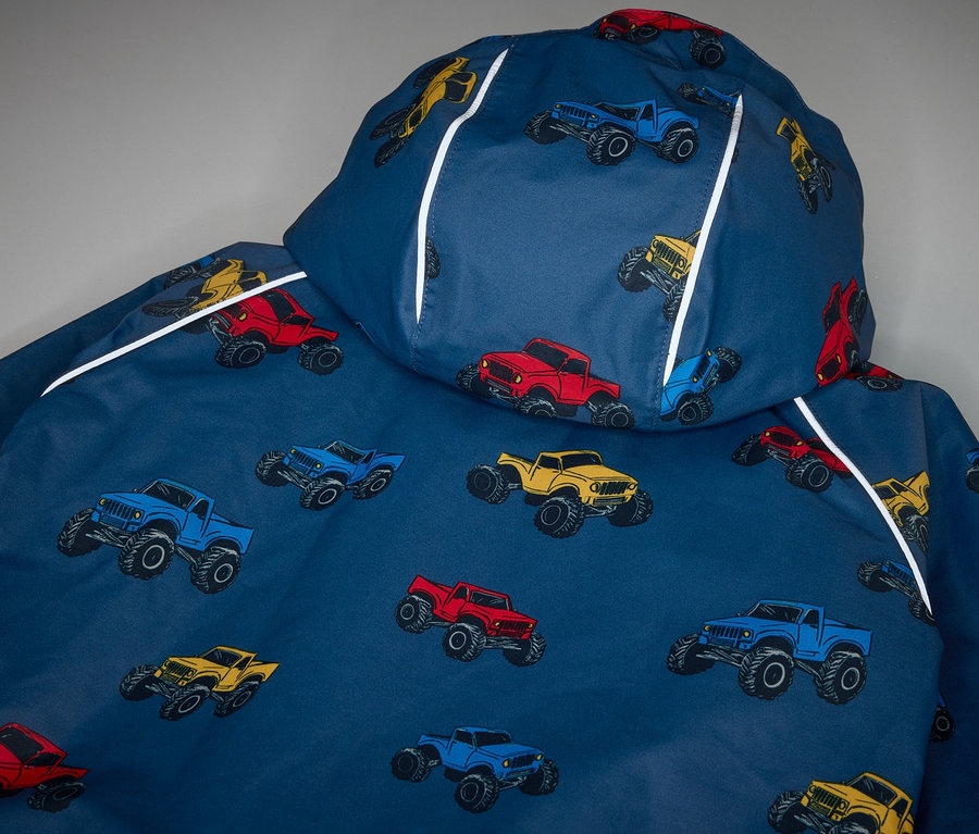 Detail dětské termo bundy do deště s potiskem monster trucků.