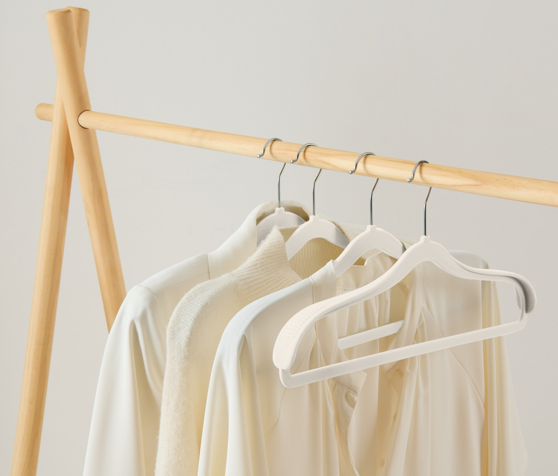 Na dřevěném věšáku visí tři bílé halenky na bílých ramínkách.