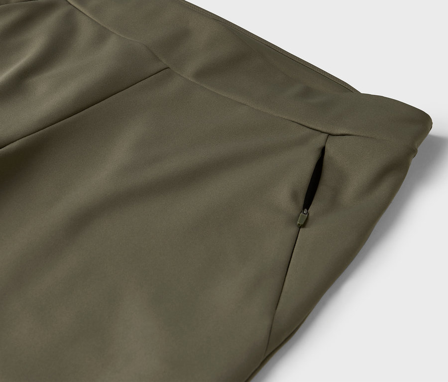 Detail olivově zelených kalhot s kapsou na zip.