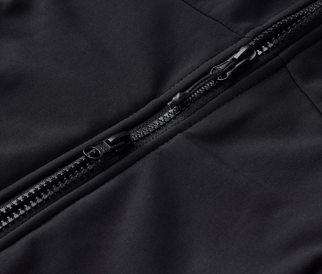 Detail černého zipu na oděvu.