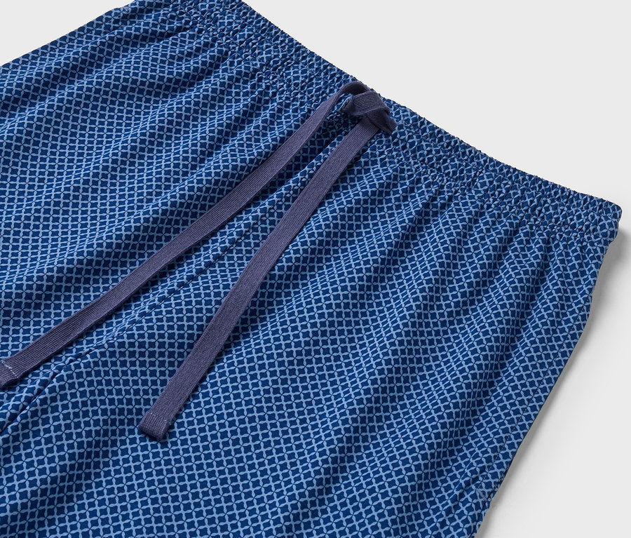 Detailní záběr na modré vzorované kalhoty s elastickým pasem a stahovací šňůrkou.