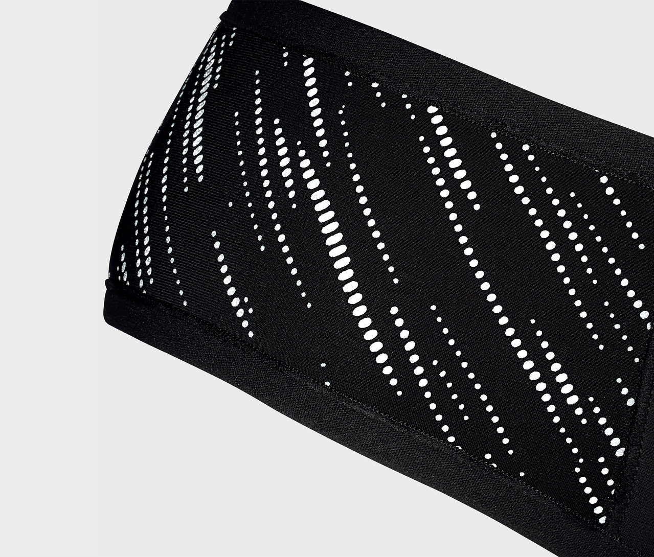 Detailní záběr na černou čelenku Windprotection-Stirnband s bílým vzorem.