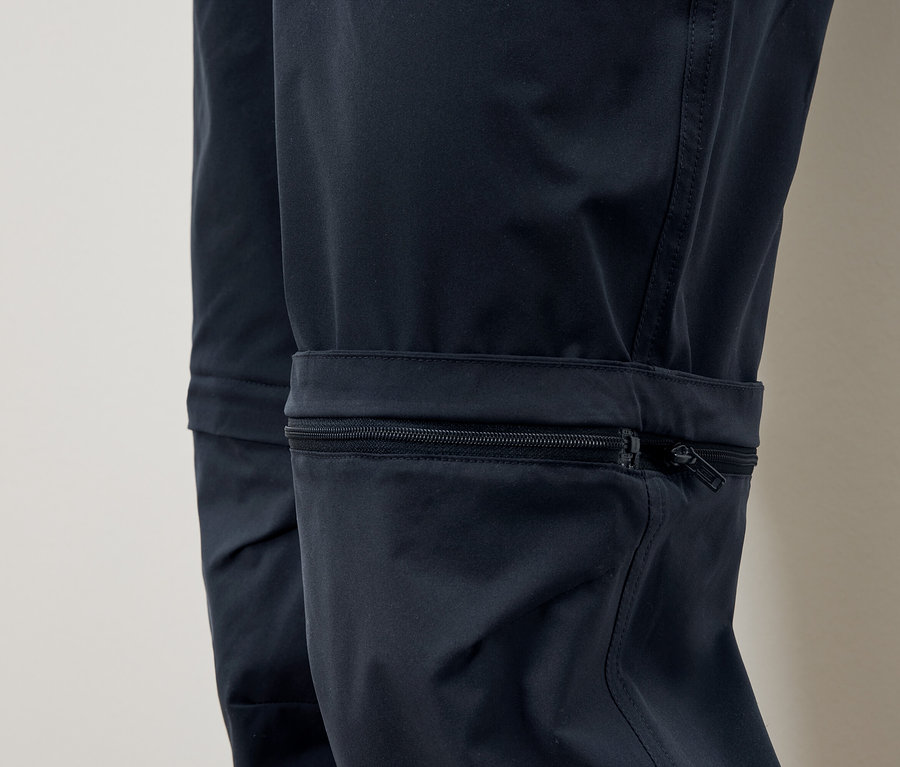 Detail modrých kalhot s kapsou na zip na nohavici.