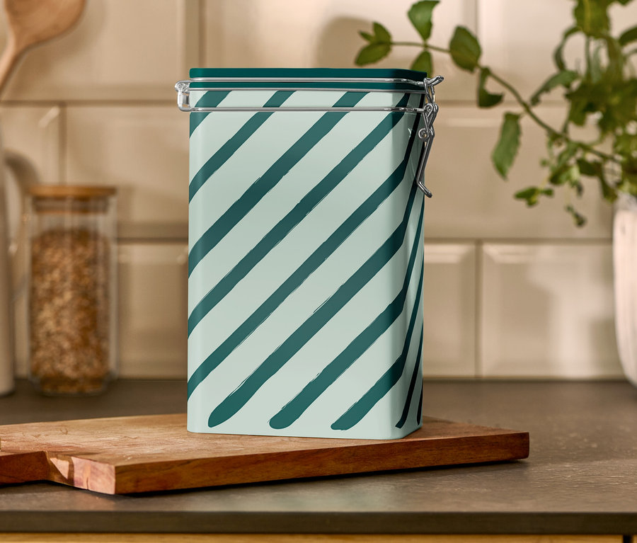 Pruhovaná dóza na kávu stojí na dřevěném prkénku.