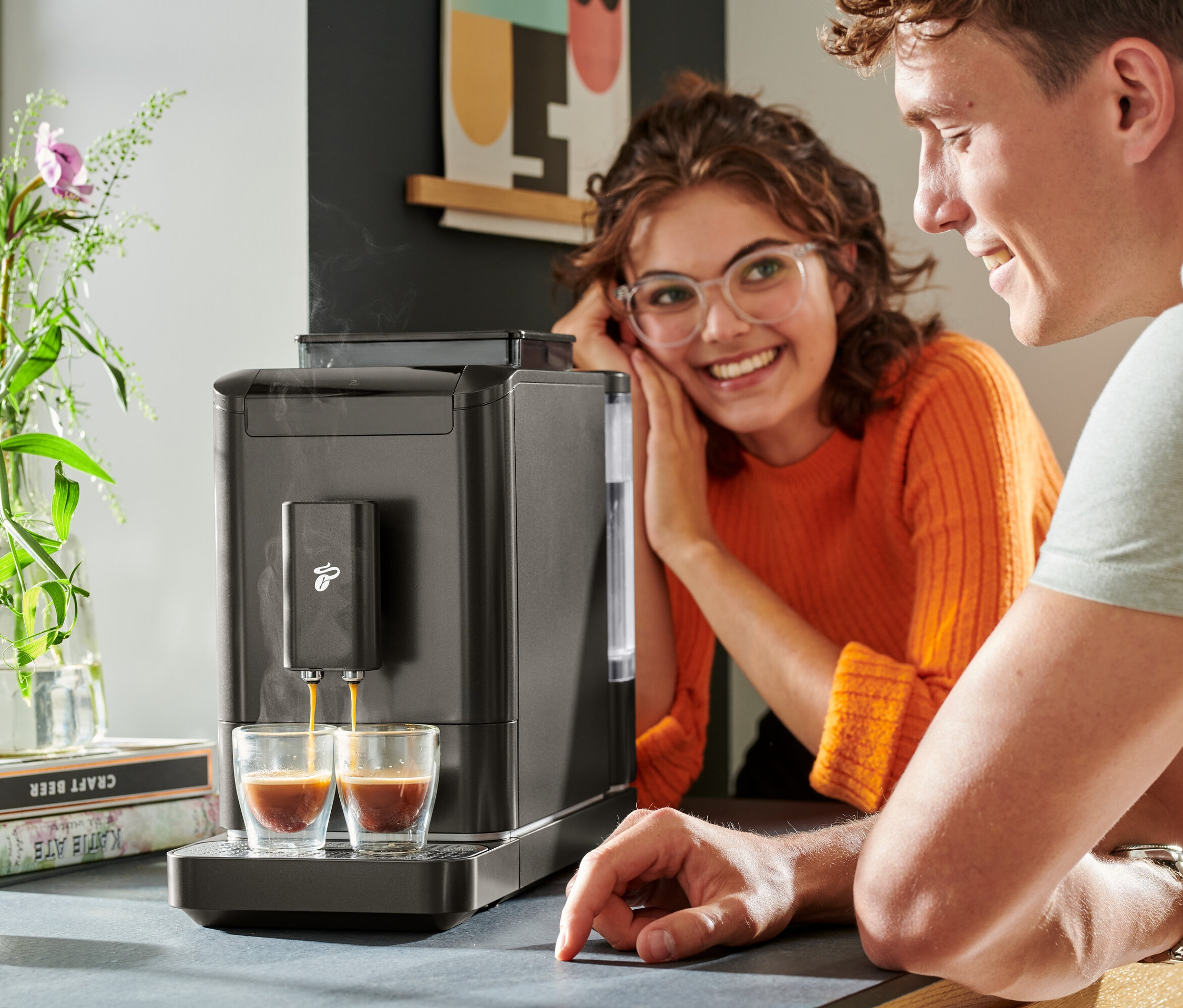 Dva lidé sledují, jak se do dvou sklenic nalévá káva z kávovaru »Esperto2 Caffè«.