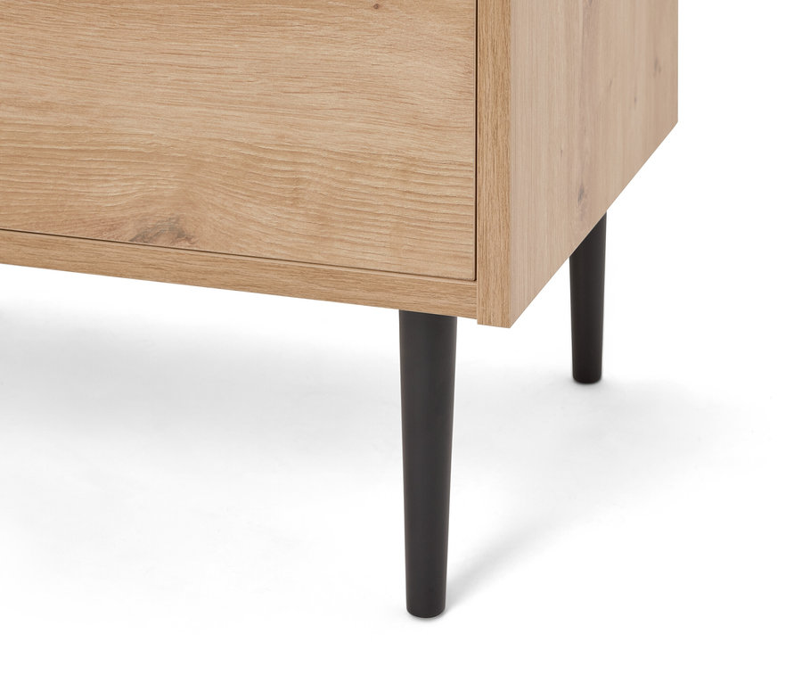 Detailní záběr na světle hnědou dřevěnou skříňku s černými nožičkami.