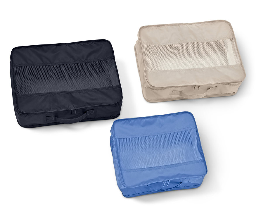 Tři obdélníkové organizéry do kufru se síťovanými okénky v námořnické modré, béžové a modré barvě leží na bílém pozadí.