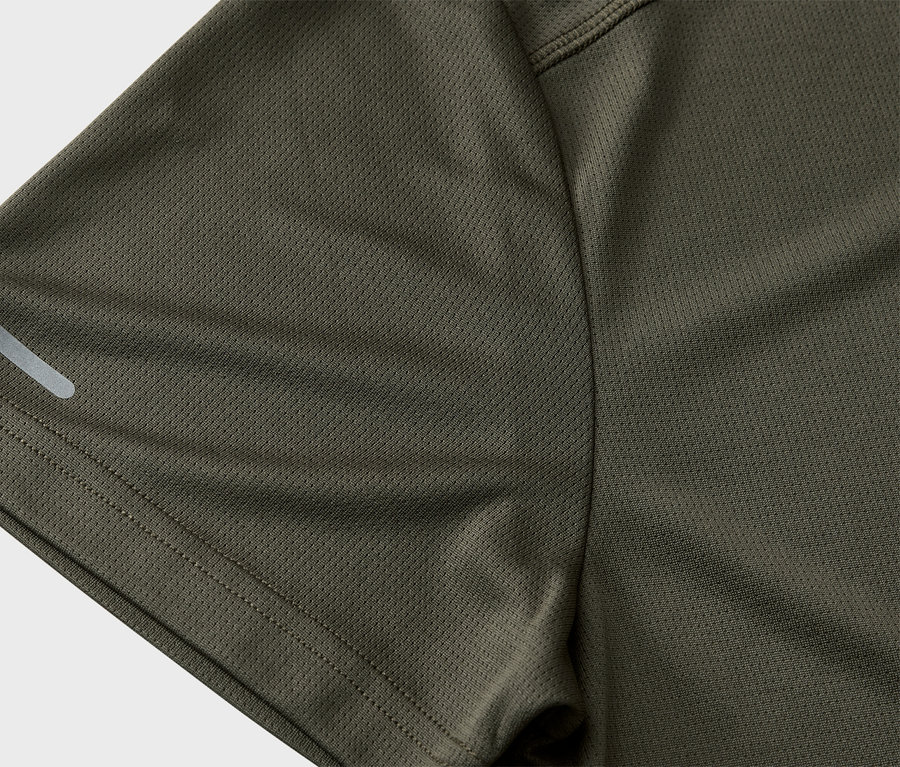 Detailní záběr na rukáv olivově zeleného sportovního trička s reflexním pruhem.