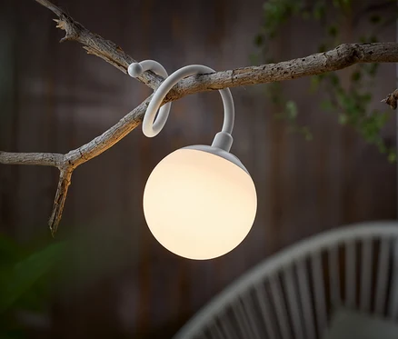 Bílá kulovitá lampa visí na větvi.