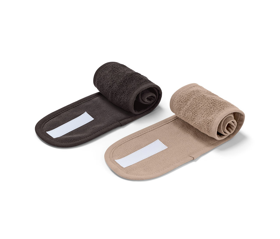 Dvě kosmetické čelenky, černá a hnědá, srolované na bílém pozadí.