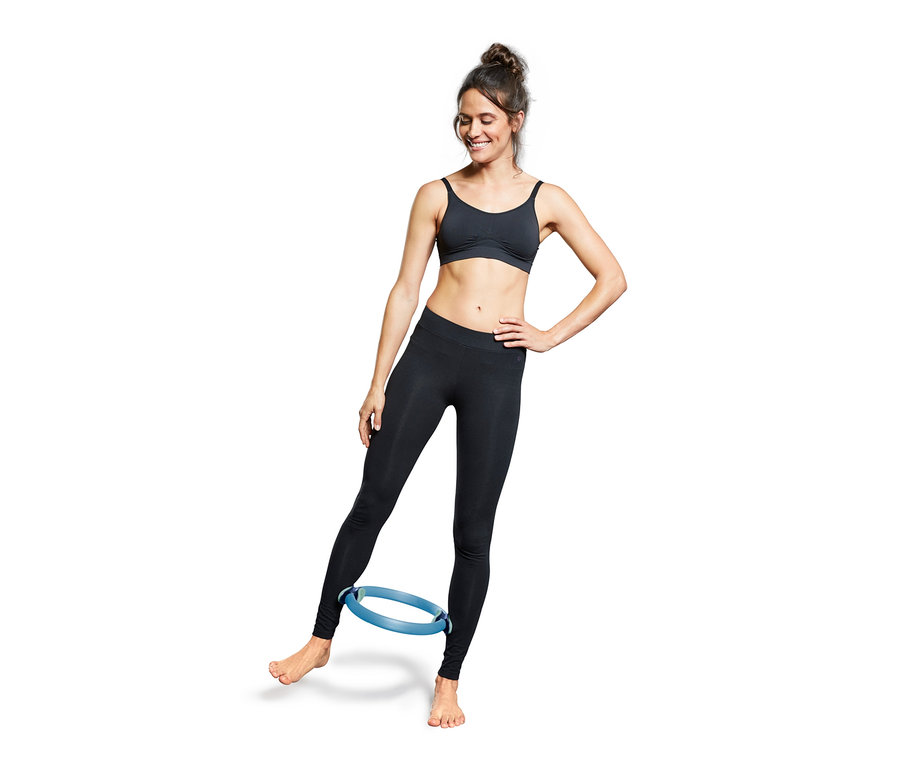 Žena cvičí s modrou obručí na pilates.