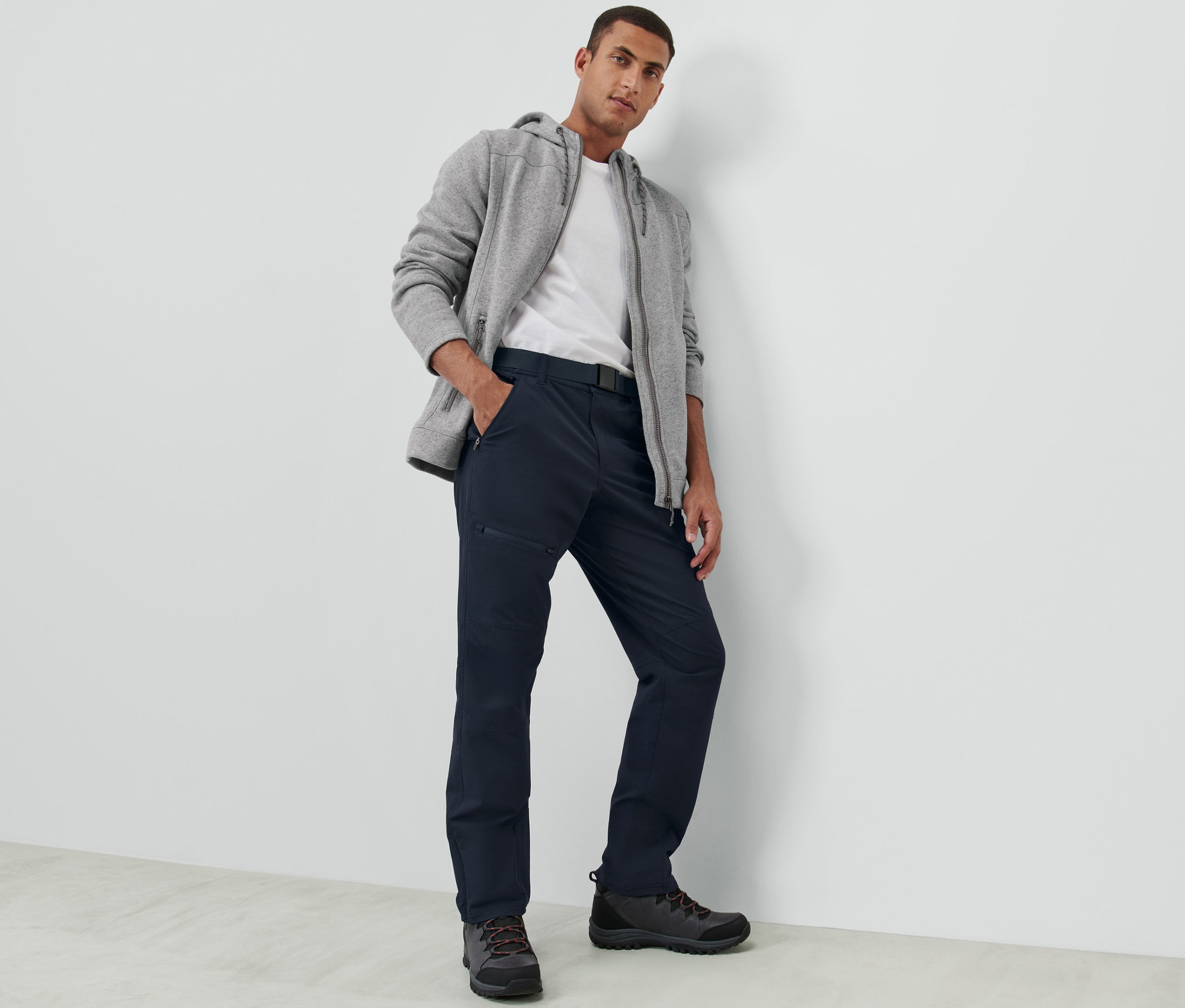 Muž pózuje na sobě tmavě modré outdoorové kalhoty.
