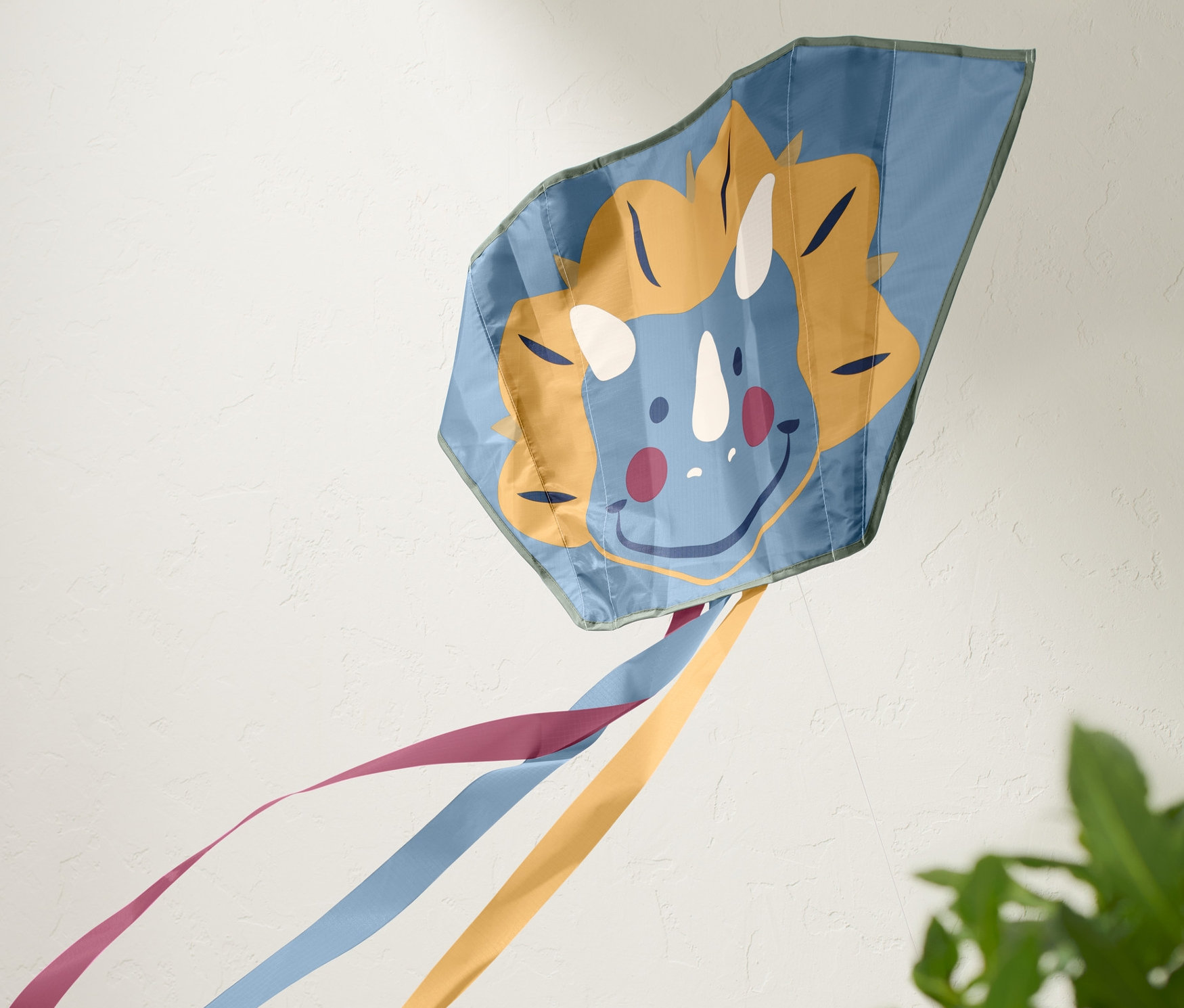 Modrý kapesní drak s obličejem dinosaura a barevnými stuhami.