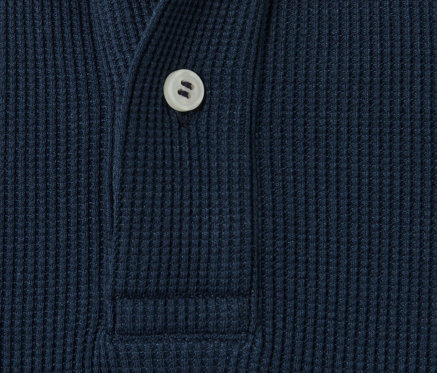 Detail modré polokošile s dlouhým rukávem s knoflíkem.