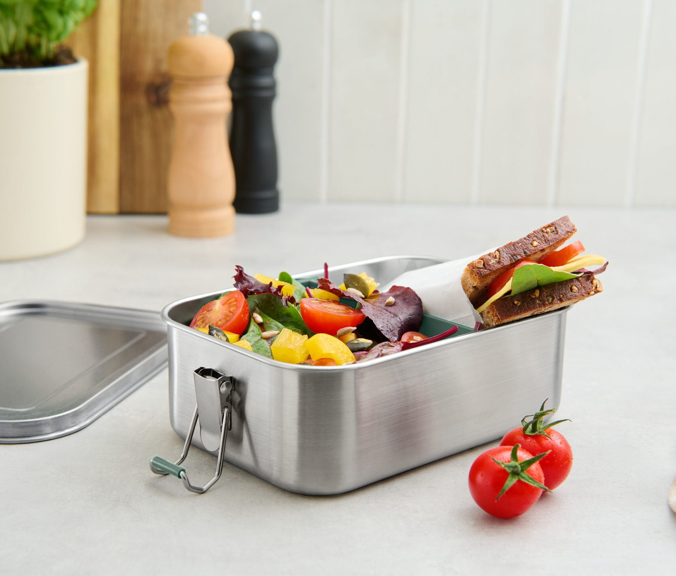 Nerezový obědový box s rajčaty, salátem a sendvičem.