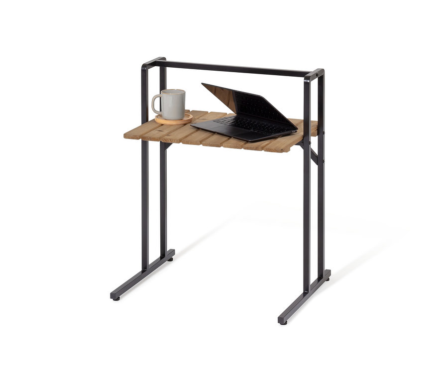 Na stolku ve tvaru C s velkou deskou leží šedý hrnek a otevřený notebook.