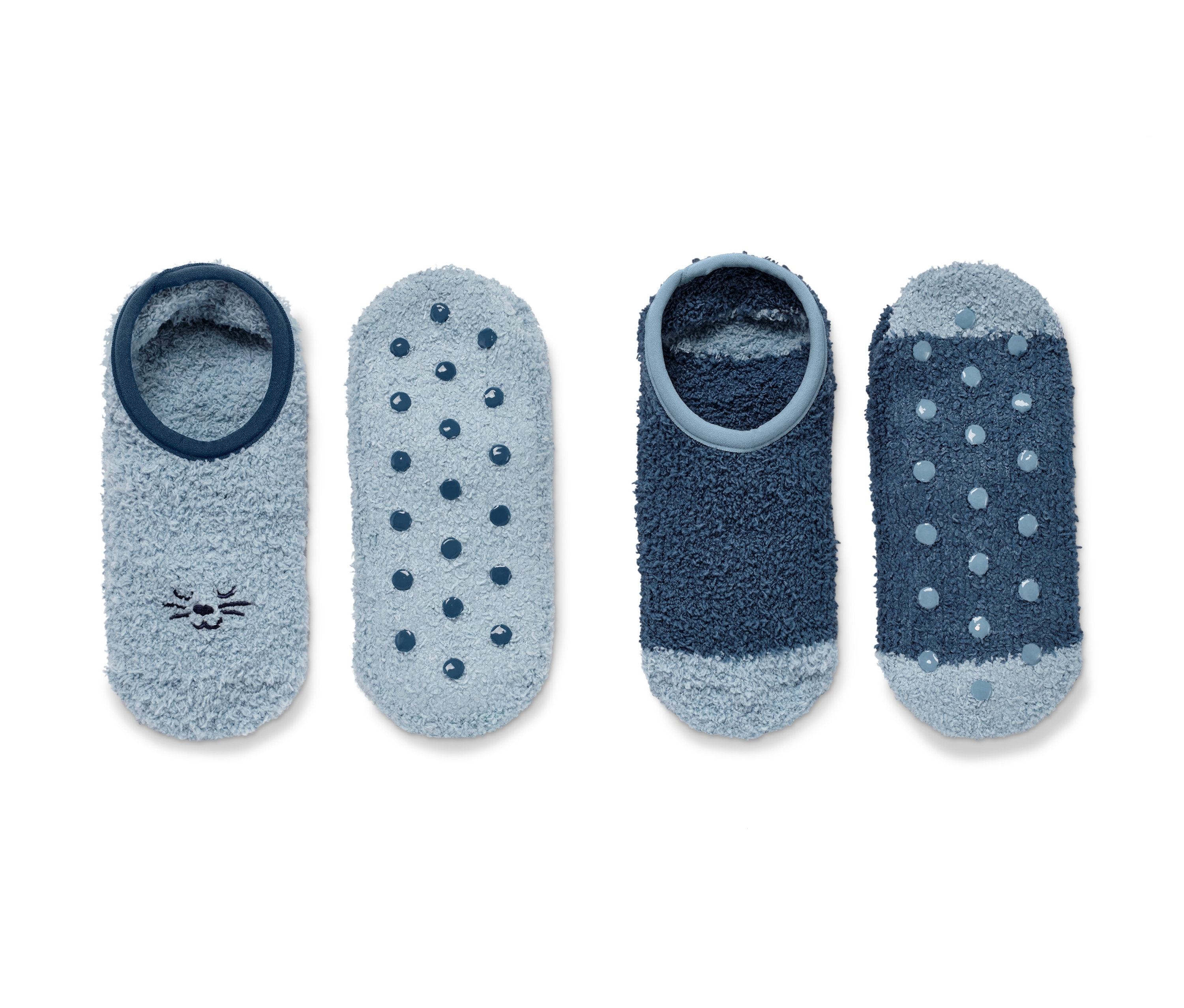Dva páry ponožkových papučí. Jeden pár je světle modrý s motivem kočky, druhý pár je tmavě modrý s puntíky.