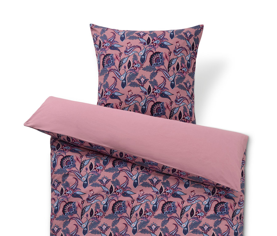 Růžové povlečení ze zimního žerzeje s květinovým vzorem a polštář nahoře.