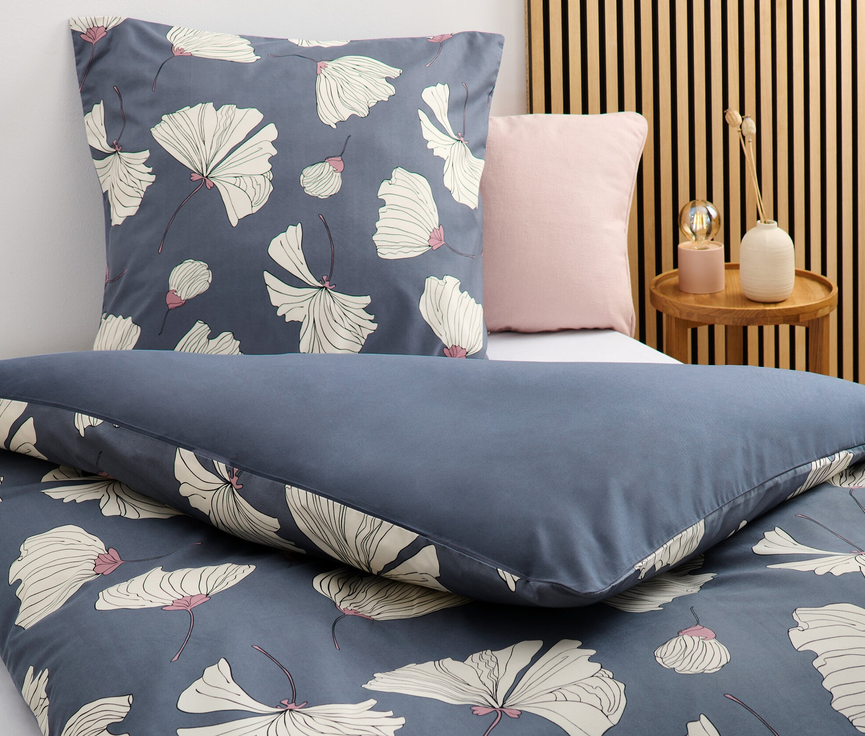 Detailní záběr na ložní soupravu z mikrovlákna s květinovým vzorem v modré barvě, standardní a nadměrné velikosti.