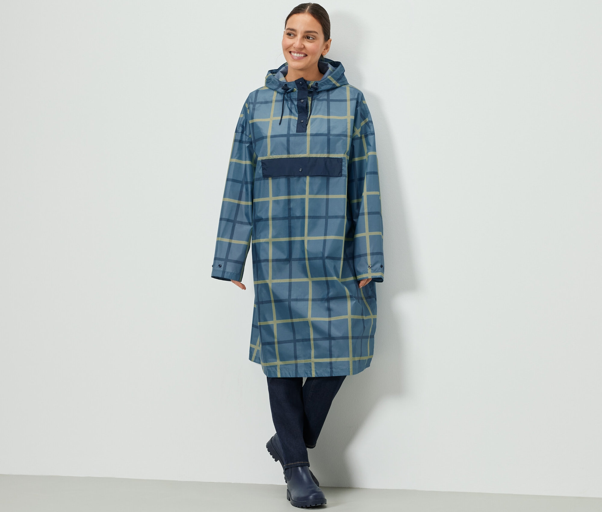 Žena má na sobě kostkované pončo do deště s rukávy.