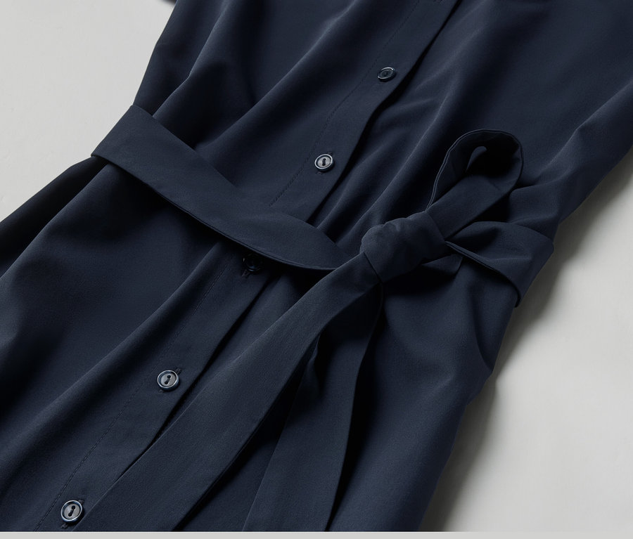 Detailní záběr na funkční šaty s knoflíky a páskem.