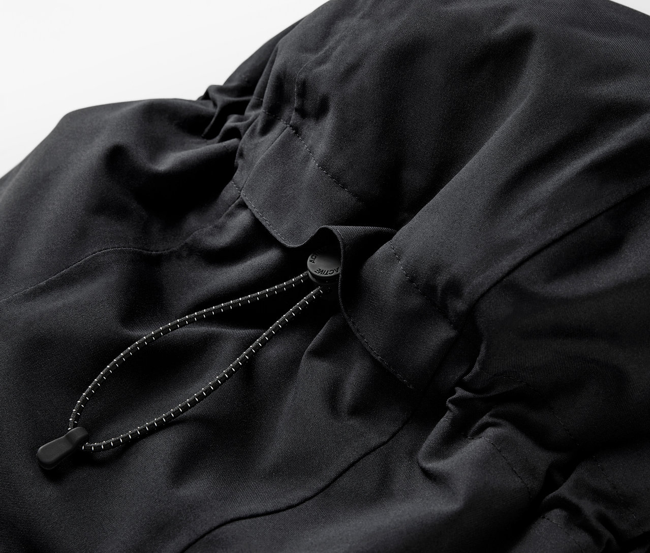 Detail černého batohu se stahovací šňůrkou.