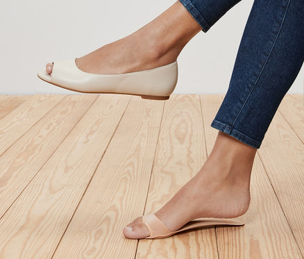 Nohy ženy v džínách, jedna noha v krémové baleríně s otevřenou špičkou a druhá v sandálu s páskem. Vložky do bot se stélkou, 1 pár, jsou v sandálu.