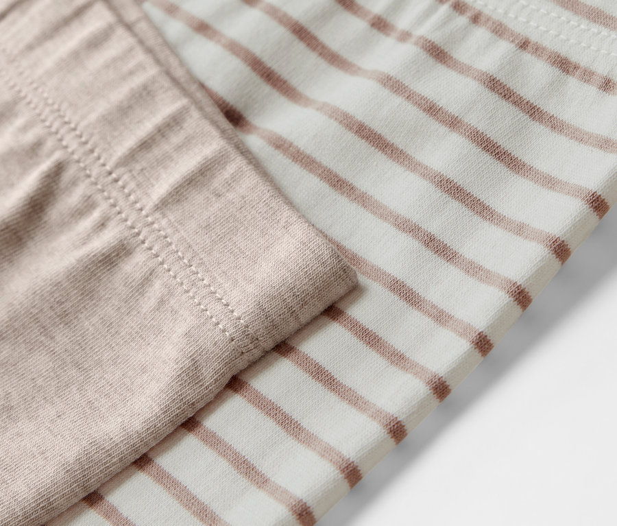 Detail dětských legín, 5 ks, jedna béžová, druhá s hnědými proužky.