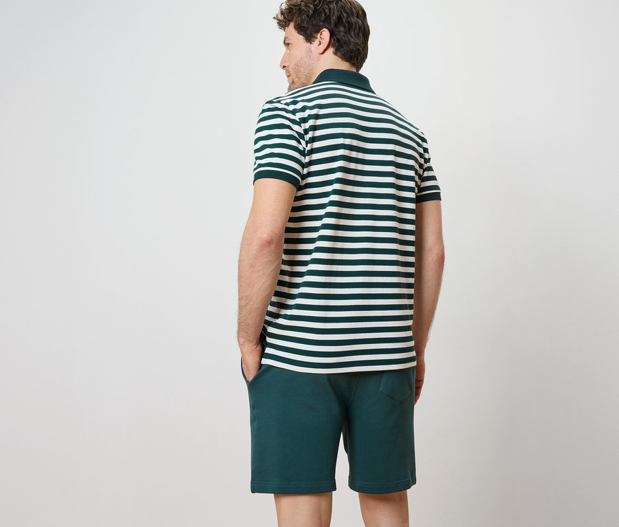 Muž zády k fotoaparátu má na sobě piké polokošili s krátkým rukávem a šortky.