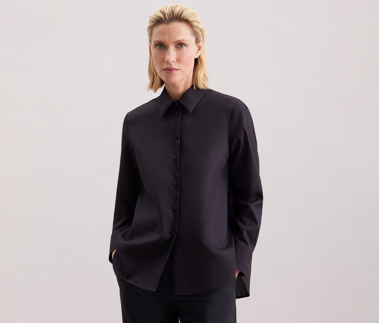 Žena má na sobě tmavě modrou halenku Seidensticker regular.