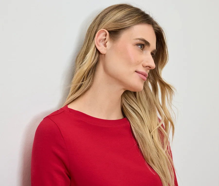 Profil ženy s blond vlasy v červeném tričku.